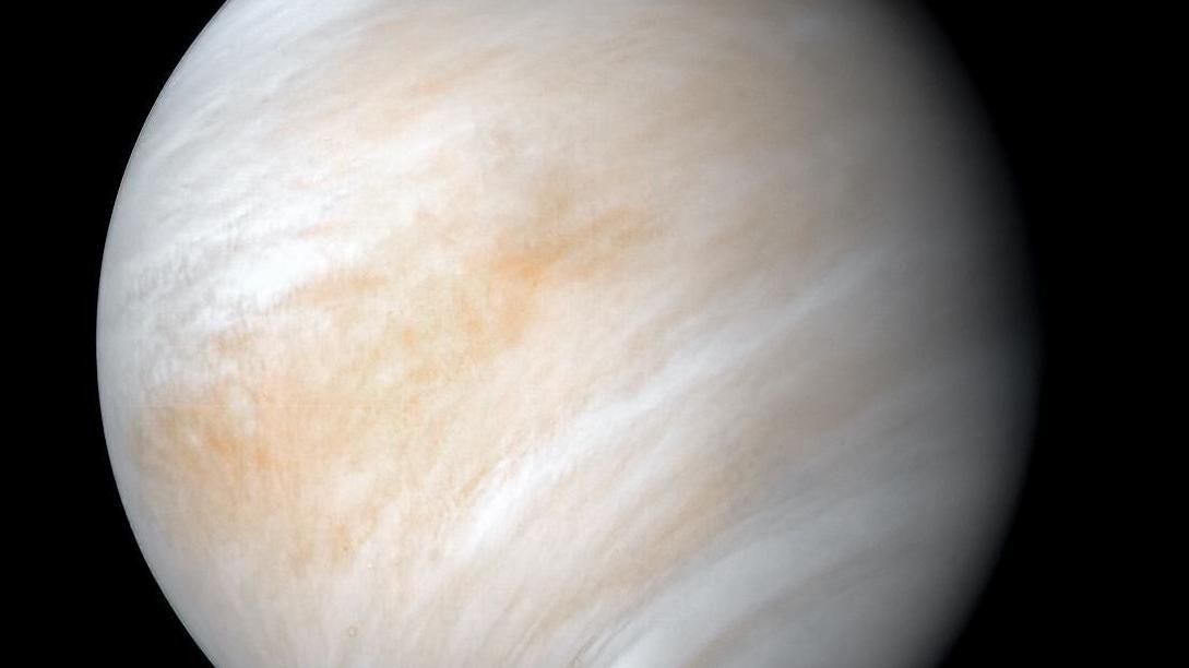 Planet with white and very light orange streaks against a black background